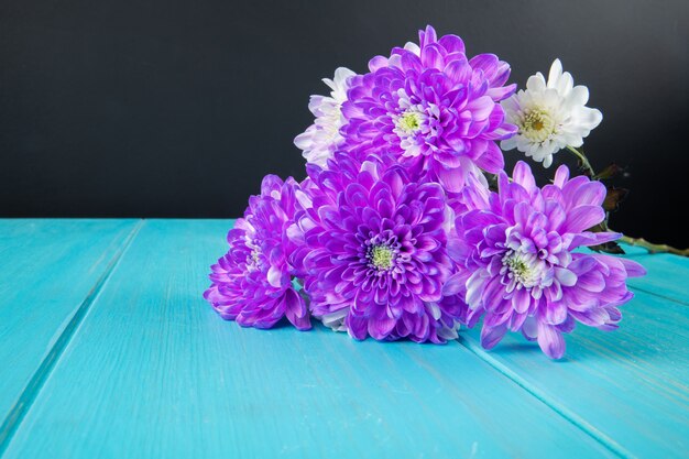 Seitenansicht des Blumenstraußes der violetten und weißen Farbe Chrysanthemenblumen lokalisiert auf blauem hölzernem Hintergrund