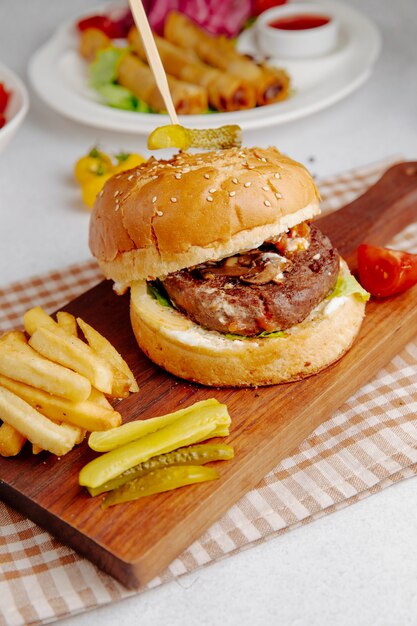 Seitenansicht des Burgers mit Pommes Frites auf einem Holzbrett