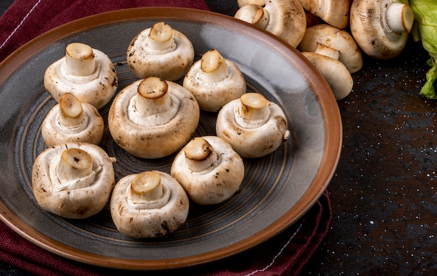 Seitenansicht des Champignons der frischen Pilze auf Keramikplatte auf dem Tisch