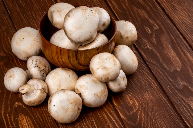 Seitenansicht des Champignons der frischen Pilze in einer Schüssel auf rustikalem hölzernen Hintergrund