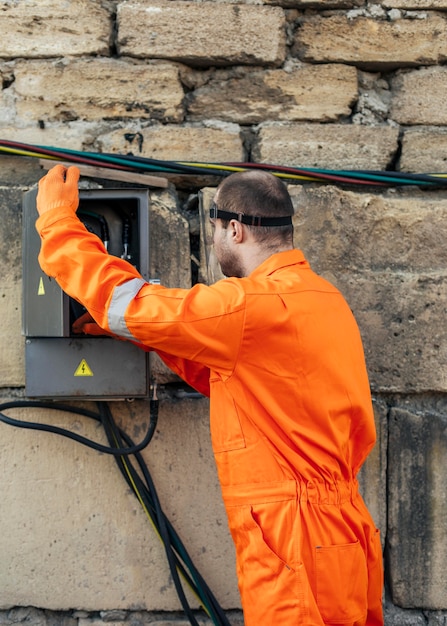 Seitenansicht des Elektrikers mit Uniform und Gesichtsschutz