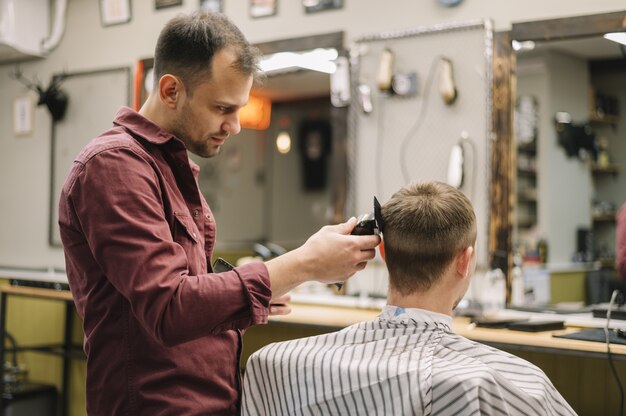 Seitenansicht des Friseurs, der einen Haarschnitt gibt