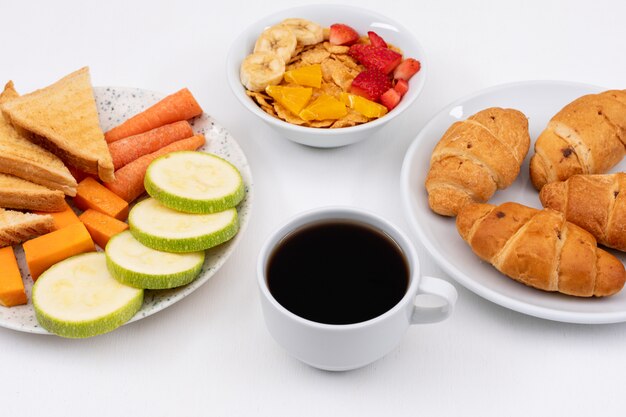 Seitenansicht des Frühstücks mit Croissants, Cornflakes und Kaffee auf weißer Fläche horizontal