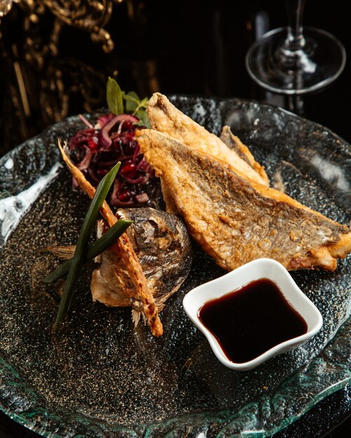 Seitenansicht des gebackenen Fischfilets mit roten Zwiebeln und Narsharab auf einem Teller