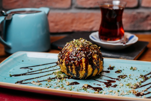 Seitenansicht des gebratenen Eises des türkischen Nachtischs bedeckt mit Schokoladensirup auf dem Tisch