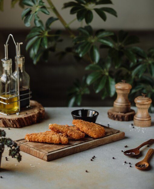 Seitenansicht des gebratenen Hühnerfilets in der Brotkrume auf einem Holzbrett