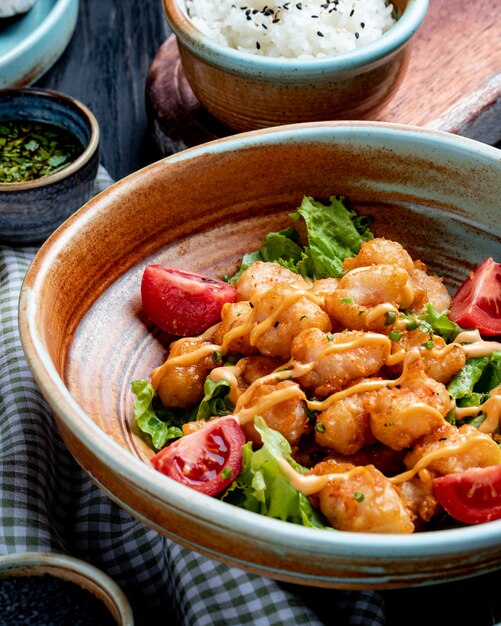 Seitenansicht des gebratenen Huhns mit Tomaten und Soße auf Salat auf einem Teller auf rustikalem