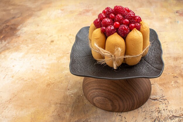 Seitenansicht des gedeckten Tisches für Kaffee- und Teezeit mit Himbeeren auf Kuchen auf gemischtem Farbtisch