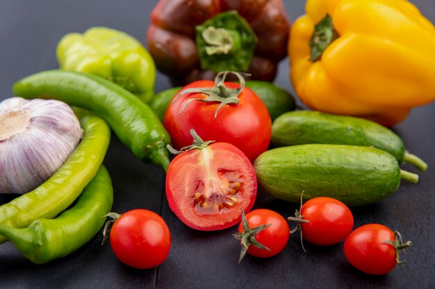 Seitenansicht des Gemüses als geschnittener und ganzer Tomatengurken-Knoblauchpfeffer auf Schwarz