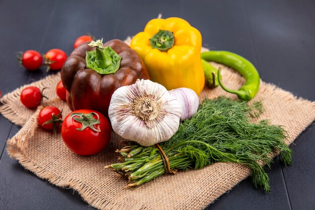 Seitenansicht des Gemüses als Pfeffer-Knoblauch-Dill-Tomate auf Sackleinen auf Schwarz