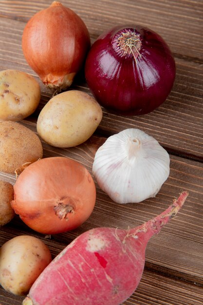 Seitenansicht des Gemüses als Zwiebelkartoffelknoblauch und Rettich auf hölzernem Hintergrund