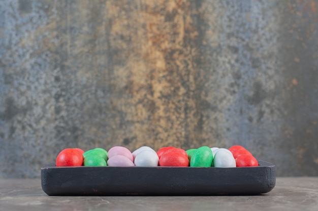 Kostenloses Foto seitenansicht des haufens von bunten süßen bonbons auf holzplatte.