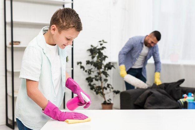 Seitenansicht des Jungen, der das Haus entlang seines Vaters säubert