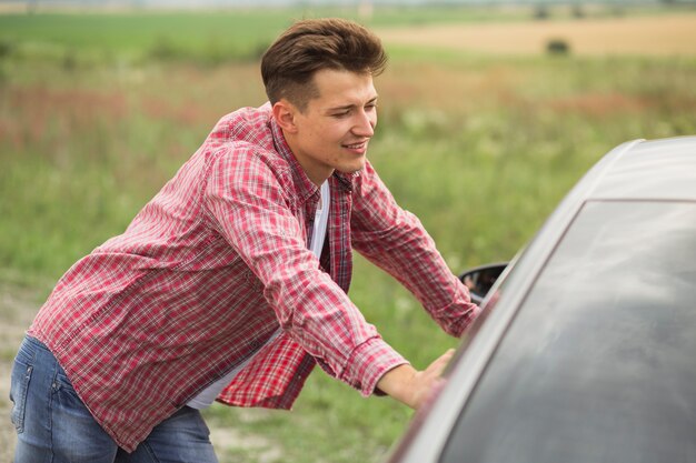 Seitenansicht des jungen Mannes stehend nahe dem Auto an draußen