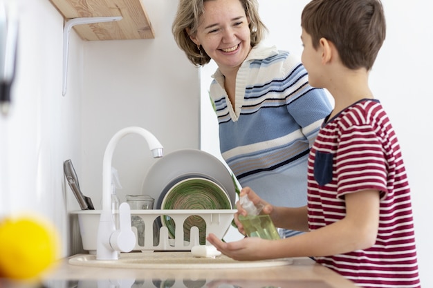 Seitenansicht des Kindes, das seine Hände wäscht, während es mit seiner Mutter spricht