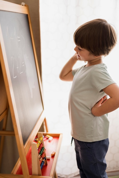 Kostenloses Foto seitenansicht des kindes zu hause, das mathematische probleme löst