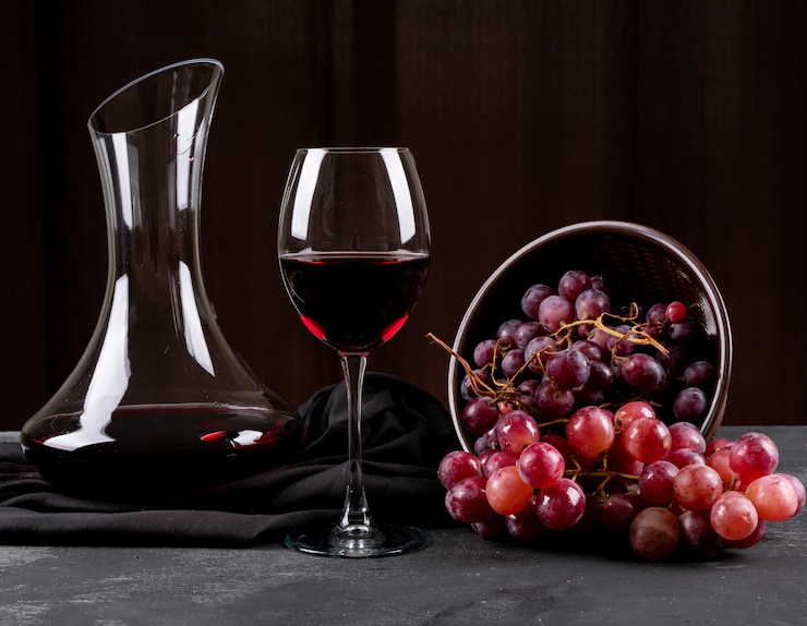 Kostenlose Foto seitenansicht des kruges mit rotwein und traube auf dunkler horizontaler