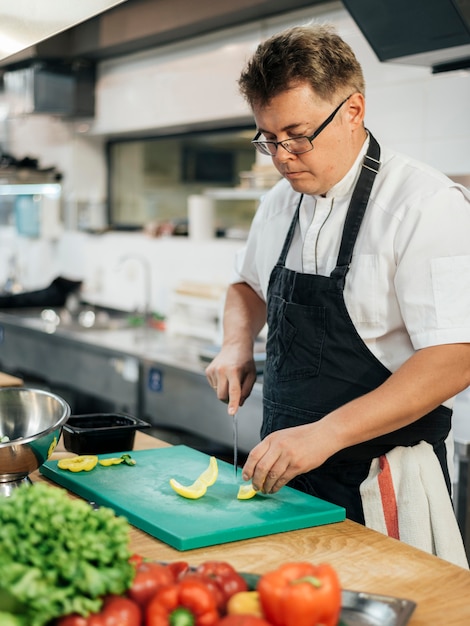 Seitenansicht des Küchenchefs, der Gemüse schneidet