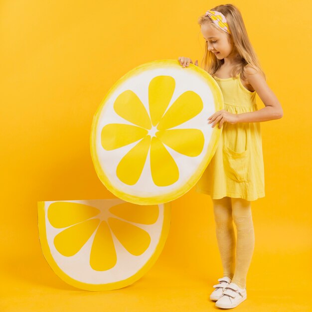 Seitenansicht des Mädchens, das Zitronenscheibendekoration hält