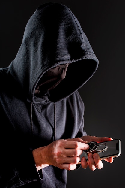 Seitenansicht des männlichen Hackers, der Smartphone und Schloss hält