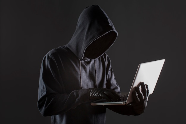 Kostenloses Foto seitenansicht des männlichen hackers mit handschuhen und laptop