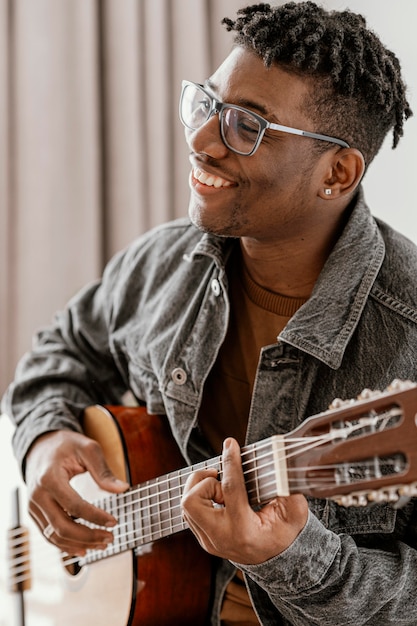 Seitenansicht des männlichen Smiley-Musikers, der zu Hause Gitarre spielt