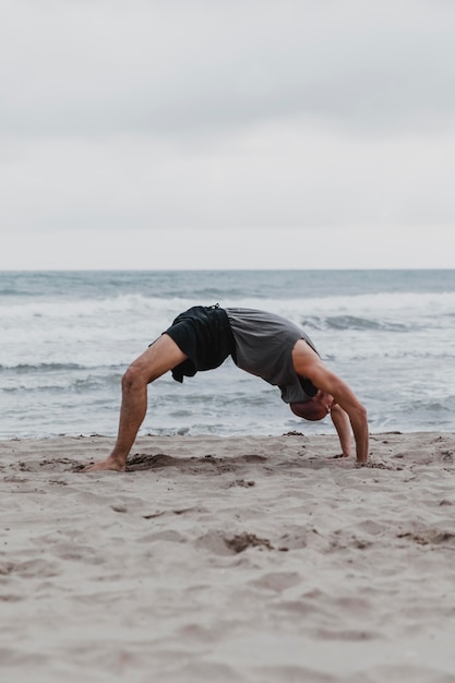 Seitenansicht des Mannes am Strand in der Yoga-Position