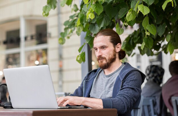 Seitenansicht des Mannes an der Terrasse, die mit Laptop arbeitet