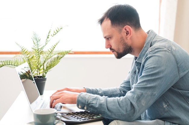 Seitenansicht des Mannes, der an seinem Laptop wotking