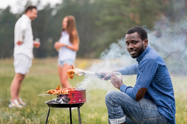 Kostenloses Foto seitenansicht des mannes, der das grillen für seine freunde besucht