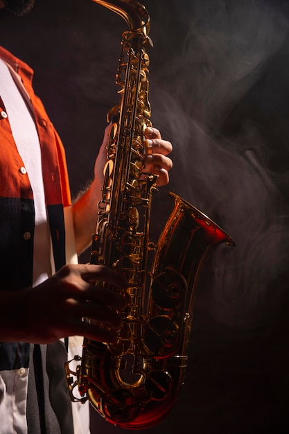 Seitenansicht des Mannes, der das Saxophon im Scheinwerferlicht spielt
