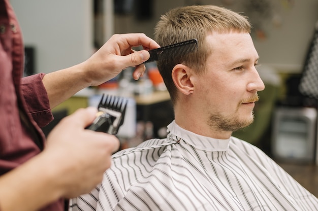 Seitenansicht des Mannes, der einen Haarschnitt bekommt