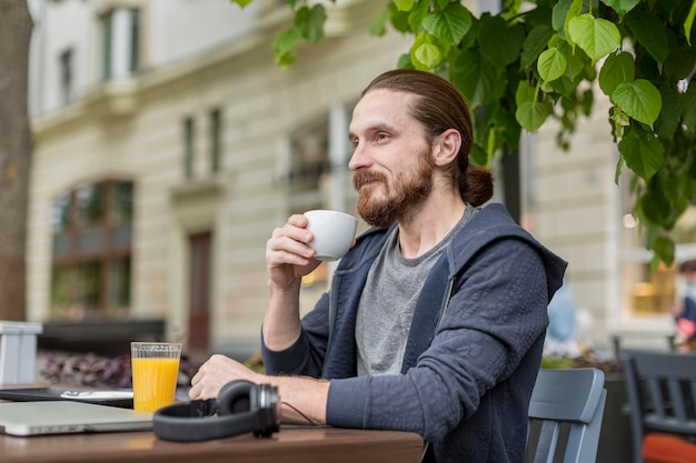 Seitenansicht des Mannes, der Kaffee an einer Stadtterrasse genießt