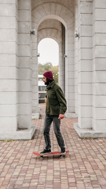 Kostenloses Foto seitenansicht des mannes, der sein skateboard in der stadt reitet