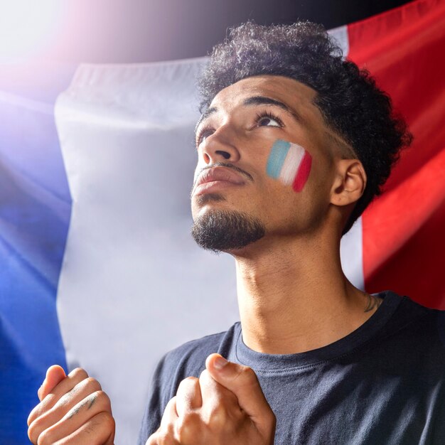 Seitenansicht des Mannes mit französischer Flagge, die nach oben schaut und Fäuste zusammenhält