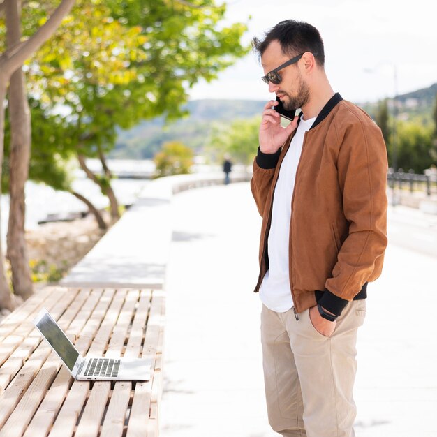 Seitenansicht des Mannes mit Smartphone und Laptop außerhalb