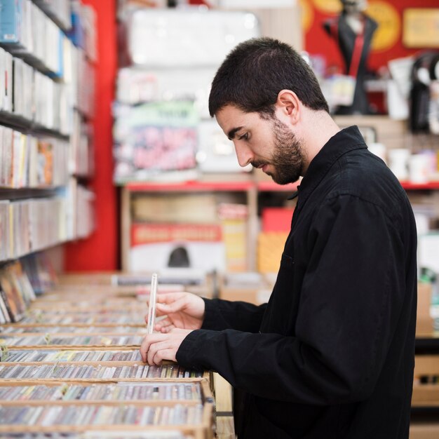 Seitenansicht des mittleren Schusses des jungen Mannes nach Vinyls im Speicher suchend