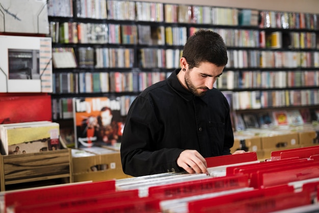 Seitenansicht des mittleren Schusses des jungen Mannes nach Vinyls im Speicher suchend