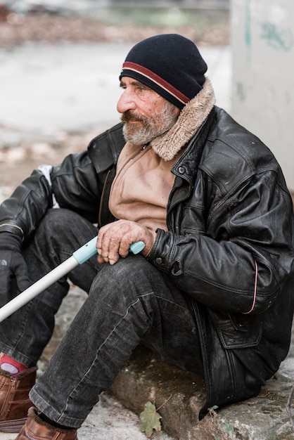 Kostenloses Foto seitenansicht des obdachlosen, der einen stock hält