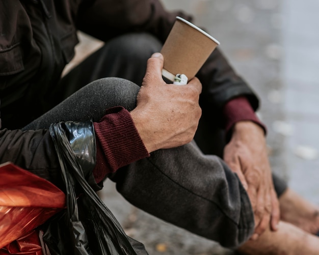 Seitenansicht des Obdachlosen, der Tasse hält