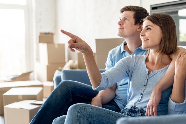 Seitenansicht des Paares auf der Couch, das auf etwas zeigt, während es auszieht