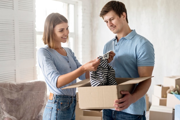 Kostenloses Foto seitenansicht des paares, das kleidung packt, um umzuziehen