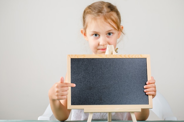 Seitenansicht des Schulkonzepts. kleines Mädchen hält und zeigt Tafel.