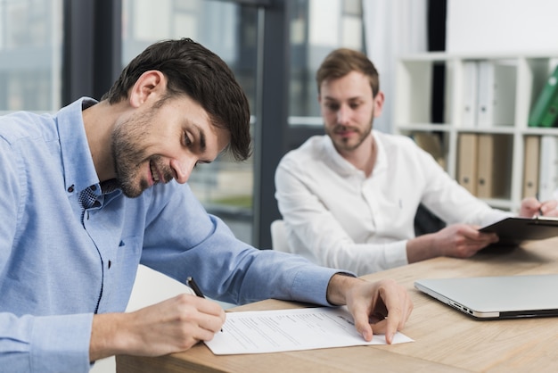 Seitenansicht des Smiley-Mannes, der Arbeitsvertrag unterzeichnet