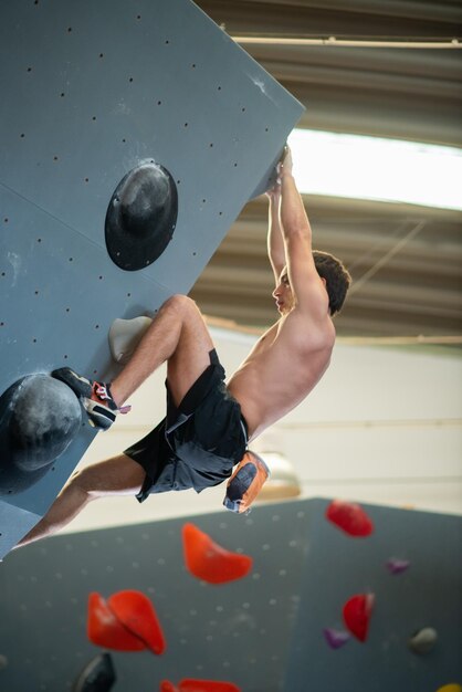 Seitenansicht des sportlichen Männertrainings. Sportler in dunkler Kleidung an der Boulderwand. Sport, Hobby, Wohlfühlkonzept