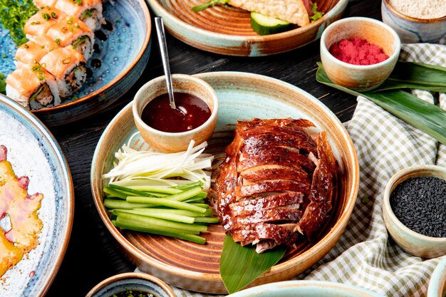Seitenansicht des traditionellen asiatischen Essens peking Ente mit Gurken und Soße auf einem Teller