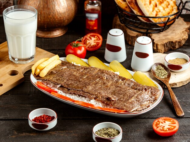 Seitenansicht des traditionellen türkischen Kebab-Ikenders auf Reis mit Gurken auf Platte