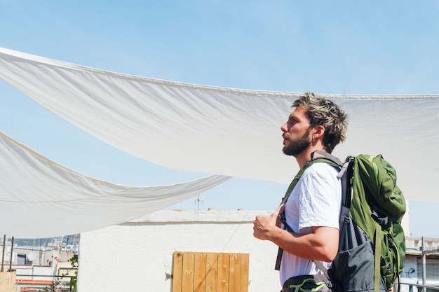 Seitenansicht des tragenden Rucksacks des jungen Mannes während des Reisens