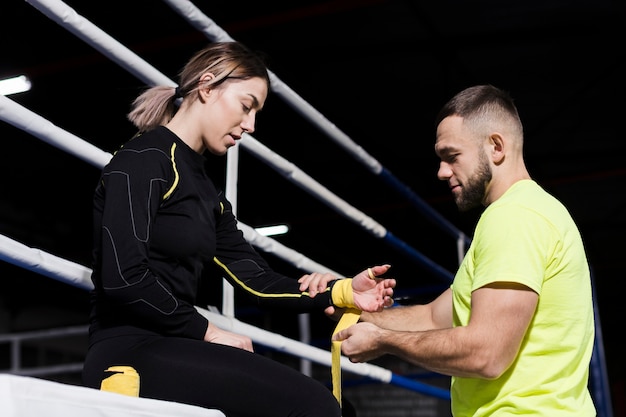 Seitenansicht des Trainers und des weiblichen Boxers, die für Praxis sich vorbereiten