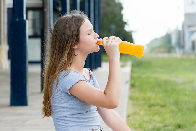 Seitenansicht des trinkenden Safts der schönen Jugendlichen im Park